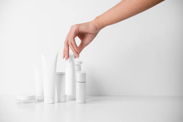 Woman picking up beauty product on white background